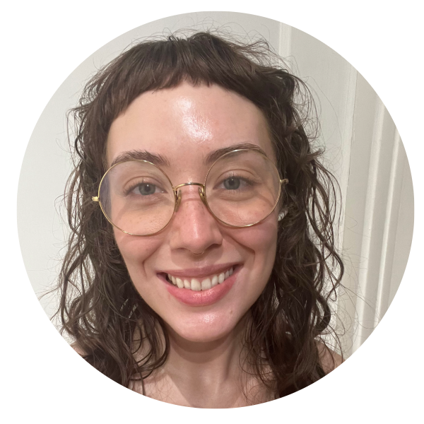Close up photo of a white woman with light brown hair wearing glasses and smiling.