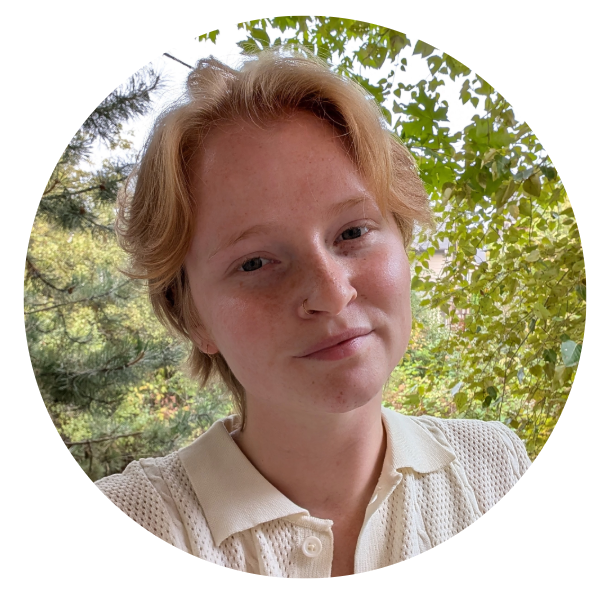 A white woman with short strawberry blonde hair wearing a white collared shirt.
