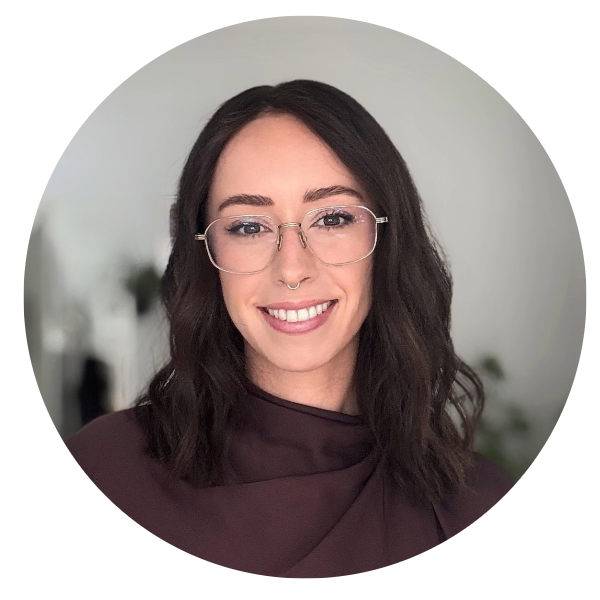 White woman with dark shoulder length hair wears glasses and brown turtle neck blouse